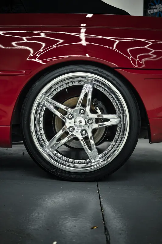 Chrome wheel and red paint reflections on a BMW 330Ci
