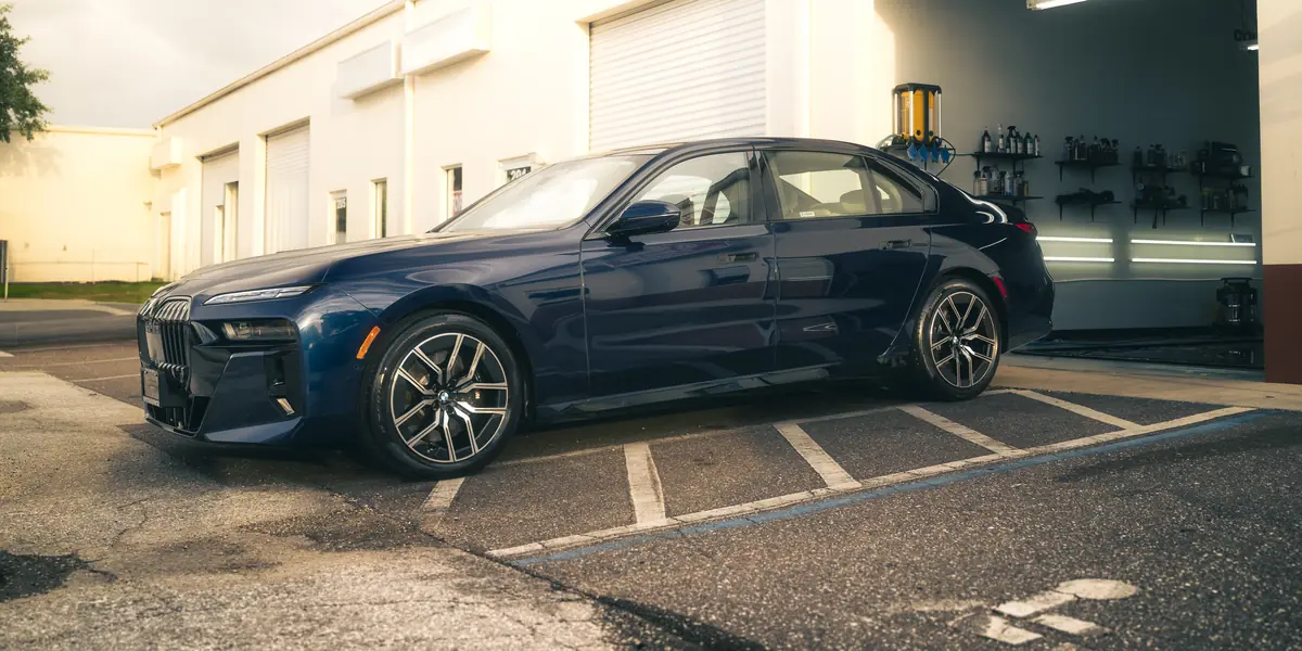 Blue BMW 760i outside 355 Auto Spa at golden hour