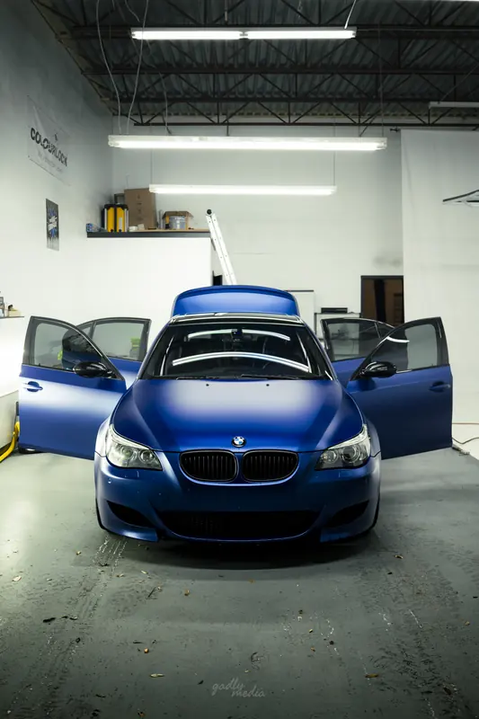 Matte blue BMW M5 with all doors open for interior detailing