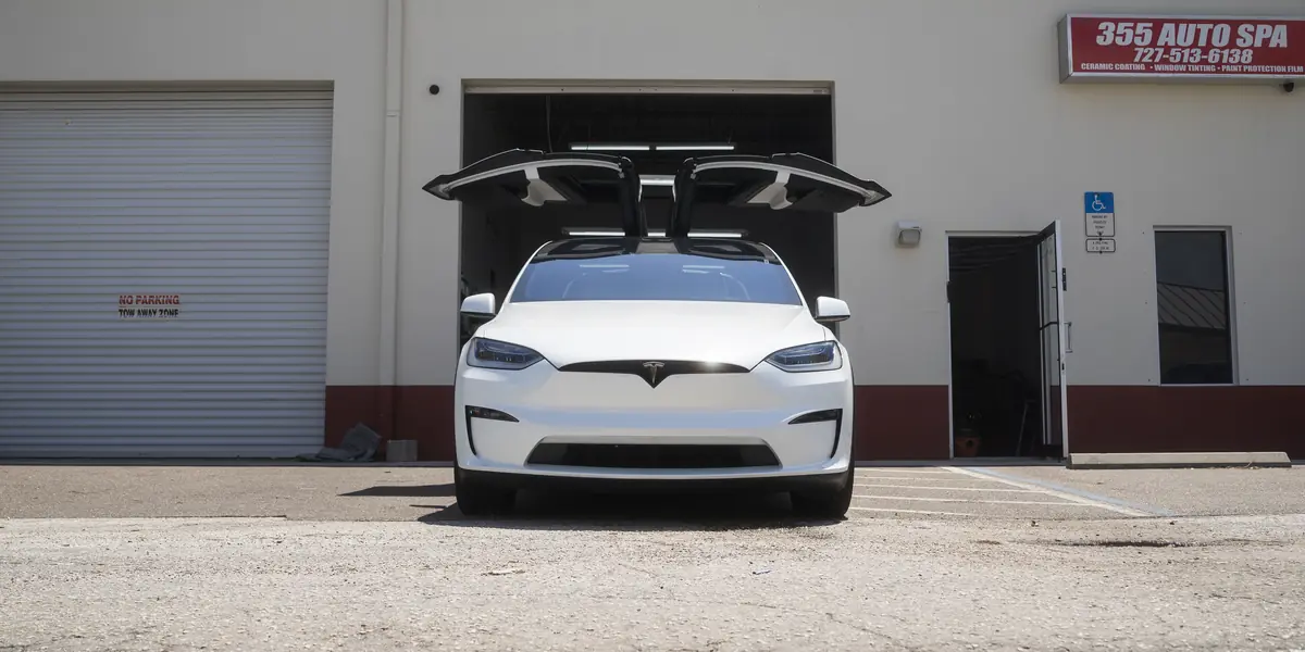 Tesla Model X Plaid with falcon-wing doors open outside the shop